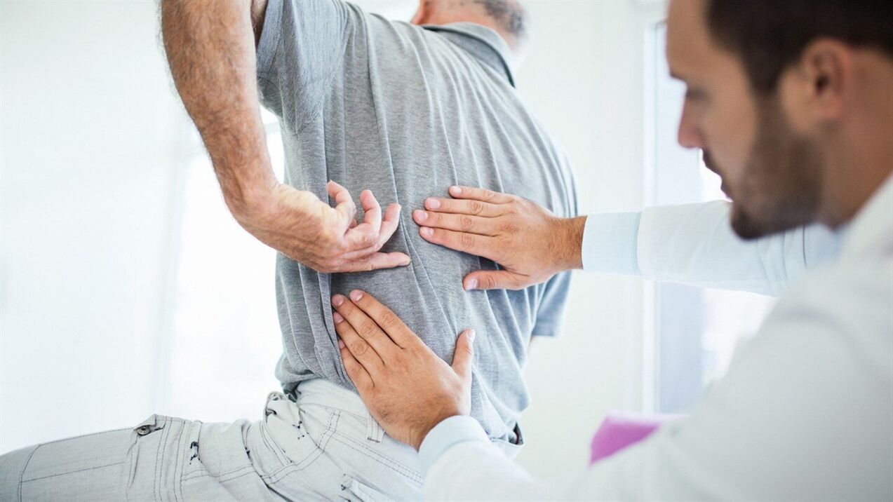 doctor examines back with lumbar osteochondrosis